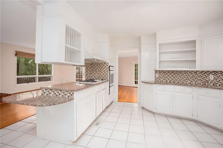 White kitchen cabinetry and granite counters define this functional cooking and dining space.