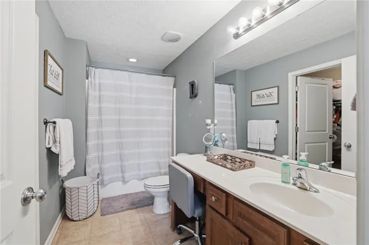 This serene bathroom offers a spacious vanity, tub-shower combination, and warm lighting.