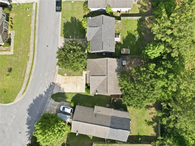 An aerial perspective reveals a residential street with homes nestled among mature trees and verdant lawns.