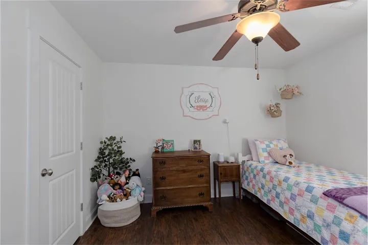 This cozy bedroom features warm wood flooring and a refreshing ceiling fan for ultimate comfort.