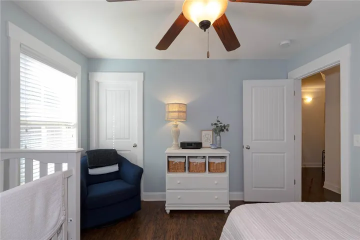 This cozy bedroom features warm wood flooring and a refreshing ceiling fan for comfort.