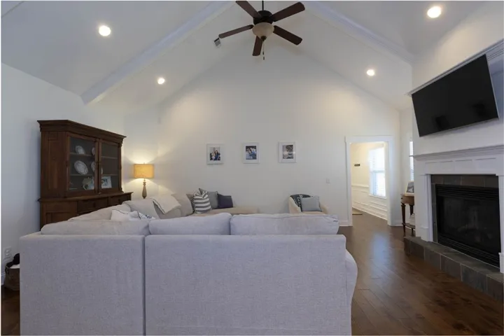 This inviting living area boasts high ceilings, elegant wood floors, and a charming fireplace.