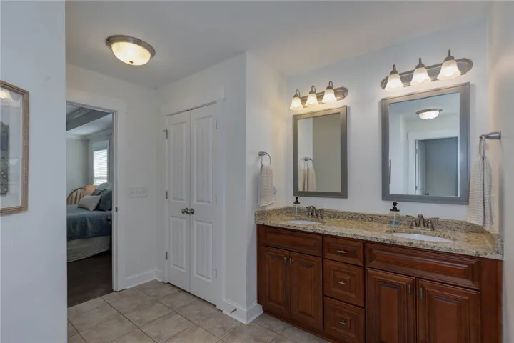This bright bathroom features a spacious dual vanity with ample storage and direct access to a cozy bedroom.
