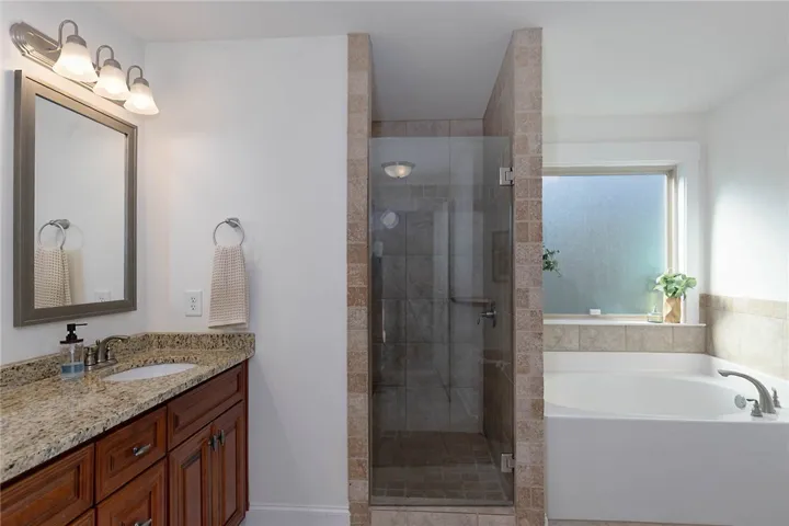 This bathroom features a contemporary shower and a soaking tub, perfect for daily routines.