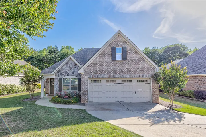 This charming home showcases a beautiful facade with a blend of brick and stone.