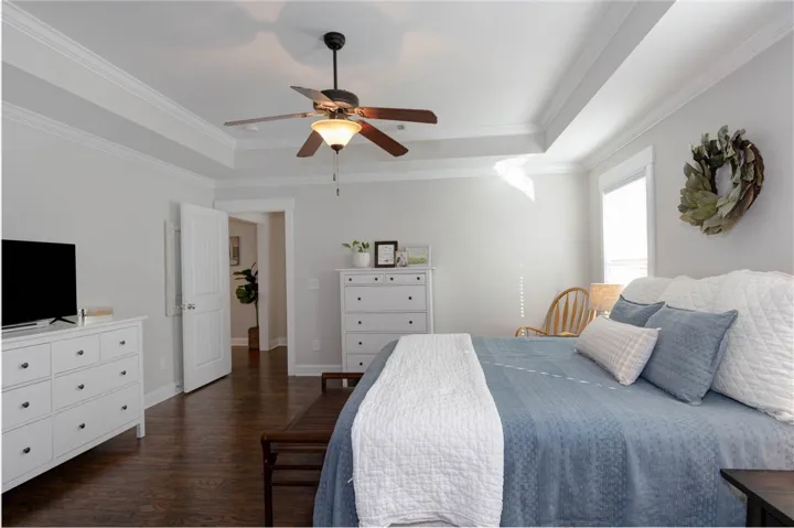 This tranquil bedroom features crown molding, a ceiling fan, and rich hardwood flooring, perfect for serene living.
