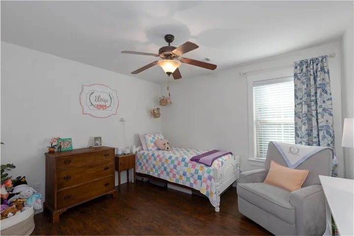 This cozy bedroom features durable flooring and a refreshing ceiling fan.