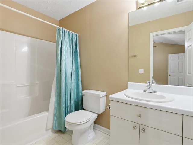 This functional bathroom features a shower-tub combination, a toilet, and a vanity with a sink.