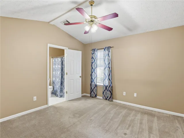 This spacious bedroom offers comfortable carpeting and a private bathroom.