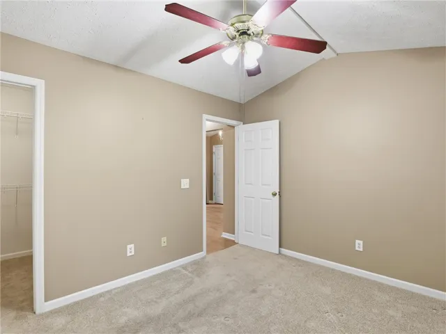 This spacious bedroom offers comfortable carpeting and a ceiling fan for optimal airflow.