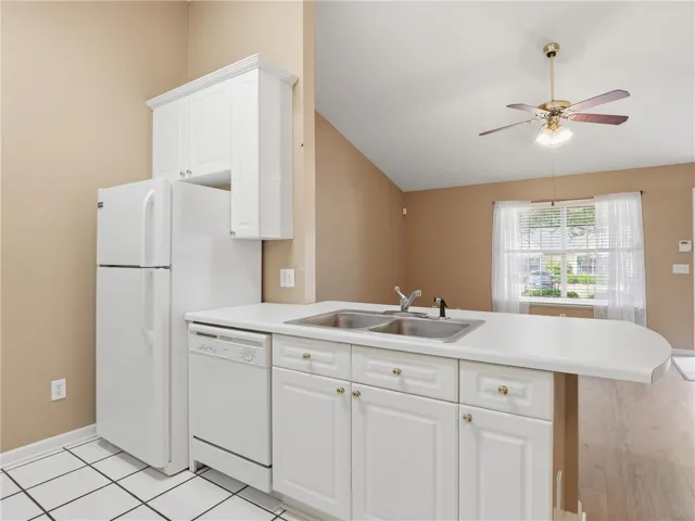 This bright kitchen features white cabinetry and appliances, alongside a practical breakfast bar.