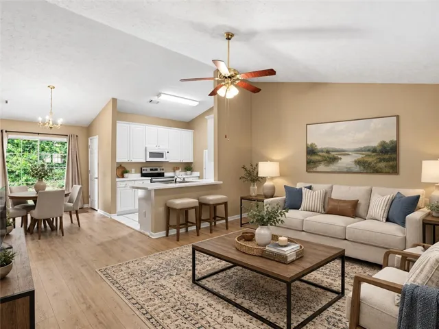 Photo has been virtually staged to help illustrate the home's potential. No structural or permanent features have been altered. An inviting open-concept living space features light wood flooring, a kitchen with a breakfast bar, and an adjacent dining area.