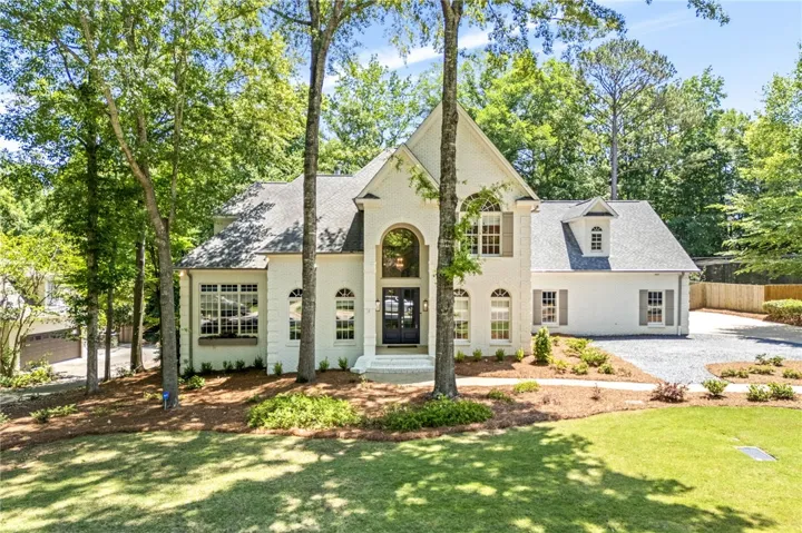 This grand residence showcases a classic design with mature trees and a pristine landscaped yard.