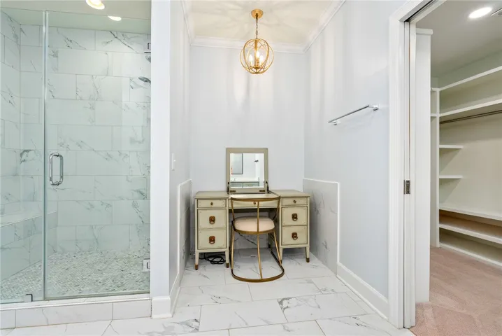 This serene primary bathroom offers a spacious walk-in shower and elegant tile flooring.