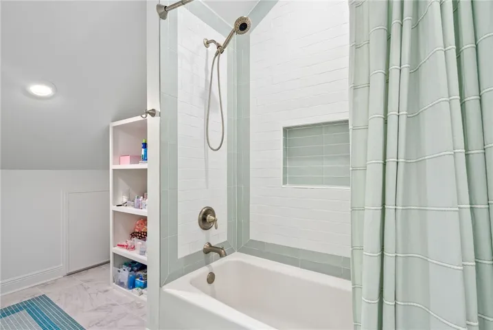 This bright bathroom features a combined tub and shower, with elegant tile work.