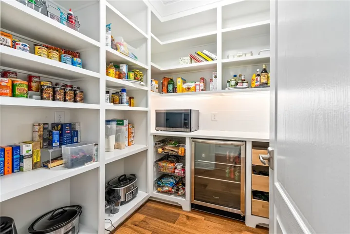 This spacious pantry provides abundant storage, an integrated mini-fridge, and a built-in microwave.