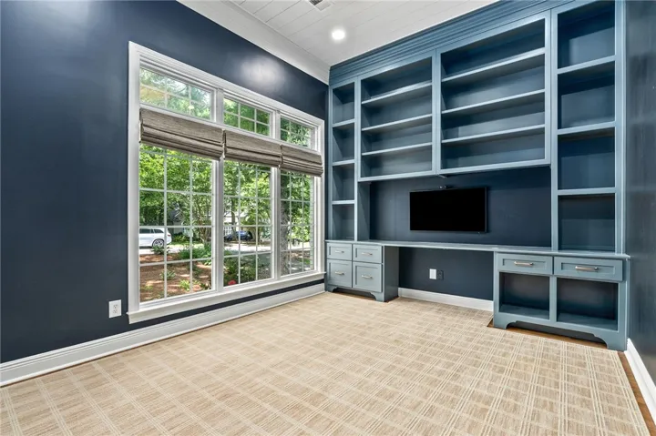This bright and airy room offers built-in storage and serene outdoor views, perfect for an office.