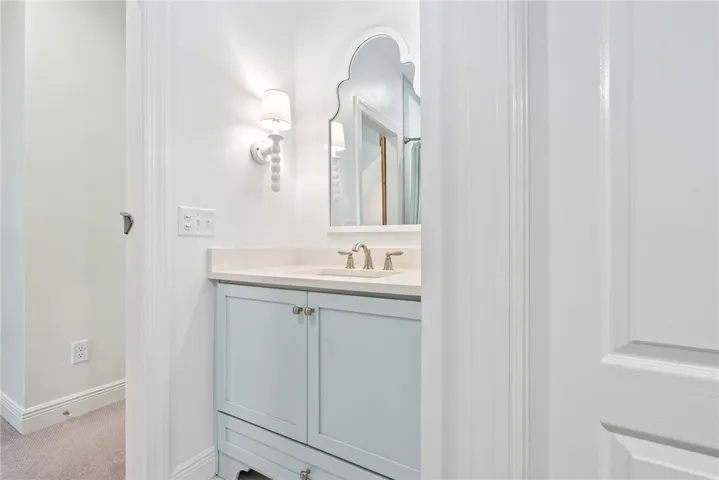 This clean and bright bathroom features a vanity with a sleek countertop and stylish mirror.