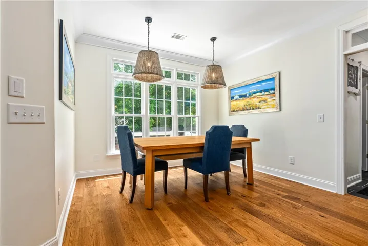 This bright dining area features warm hardwood floors and a large window overlooking lush greenery.