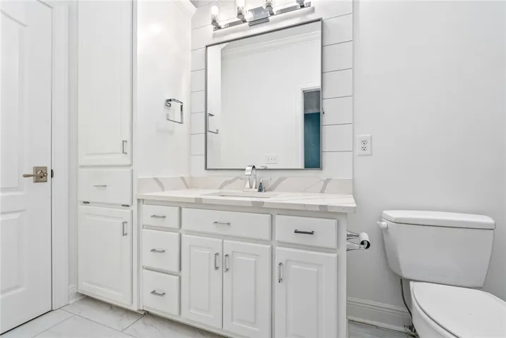 This bright bathroom features a vanity with ample storage and a sleek toilet.