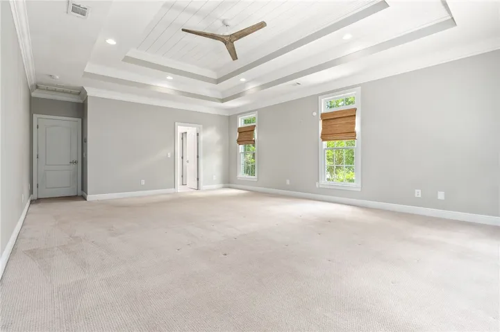 This spacious primary bedroom features a striking tray ceiling and abundant natural light.