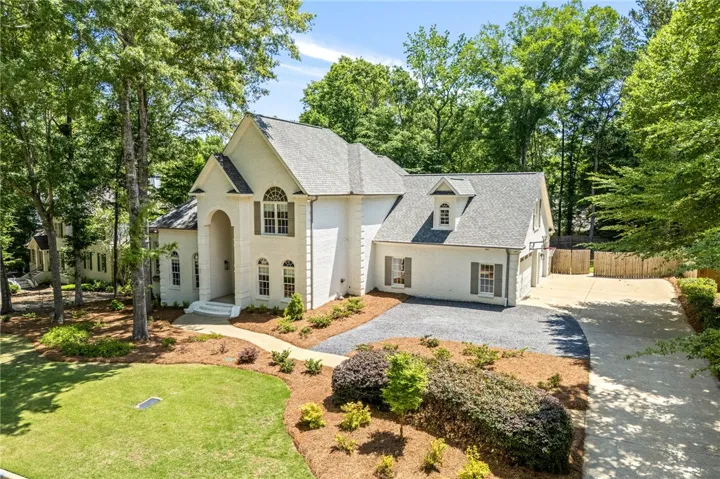 This classic white brick home boasts a lush green lawn and mature trees, offering a private oasis.