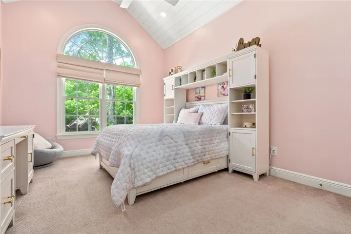 This inviting bedroom features vaulted ceilings and ample natural light, creating a bright and airy retreat.