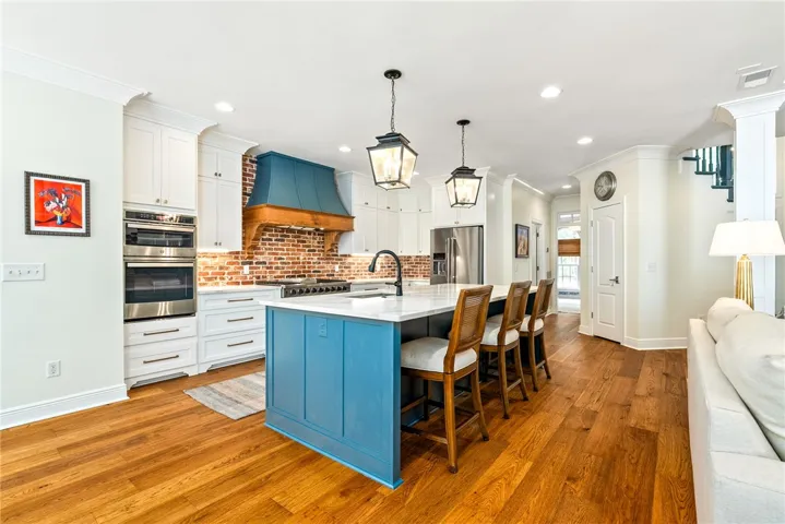 This bright kitchen features an expansive island and rich wood flooring, perfect for gatherings.