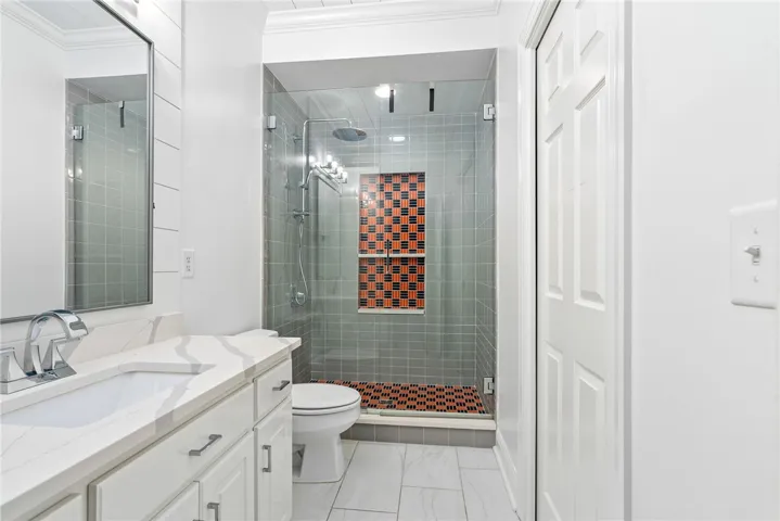 This sleek bathroom features a modern vanity and an inviting shower with unique tile accents.