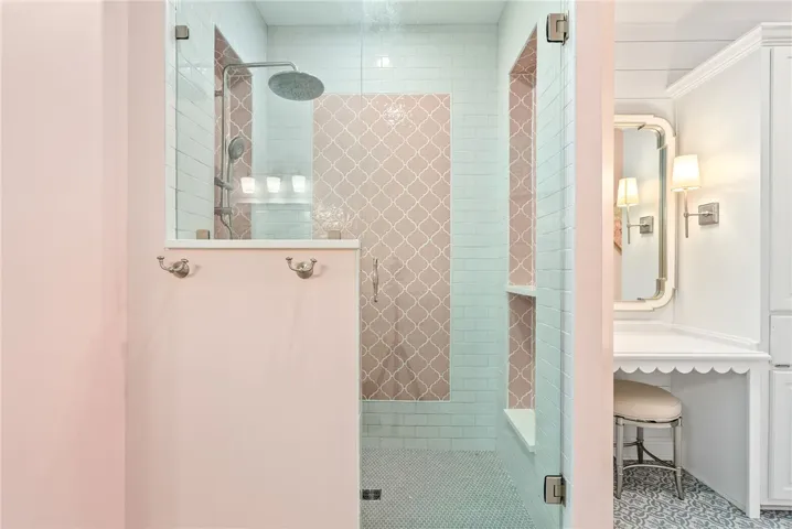 This exquisite bathroom showcases a spacious shower with delicate tiling and a charming vanity area.