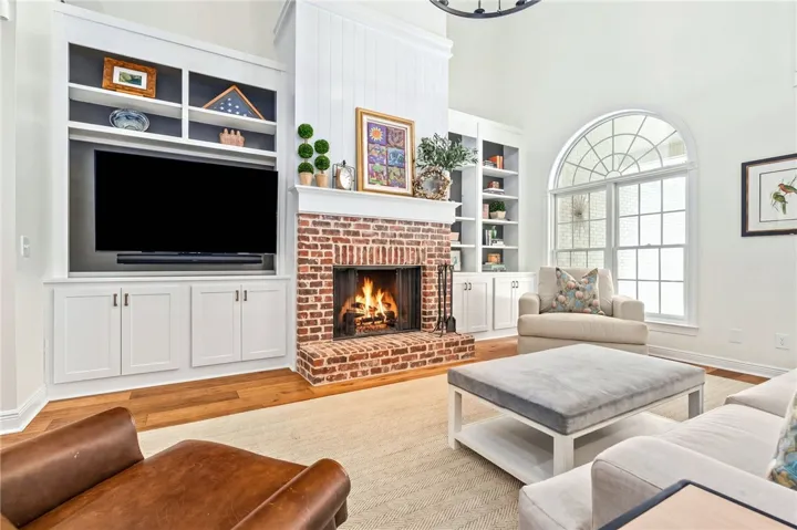 This living area features built-in shelving, a brick fireplace, and ample natural light from an arched window.