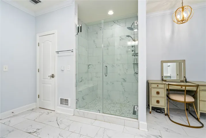 This spacious bathroom offers a glass-enclosed shower with pristine tile work and elegant flooring.