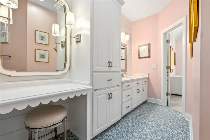 This bathroom features unique patterned tile flooring, an elegant vanity, and ample storage.