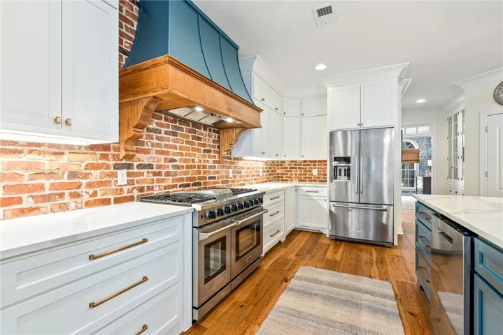 This modern kitchen features a gas range, stainless steel appliances, and a beautiful hardwood floor.