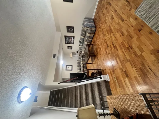 This interior hallway features rich hardwood flooring leading to a carpeted staircase.