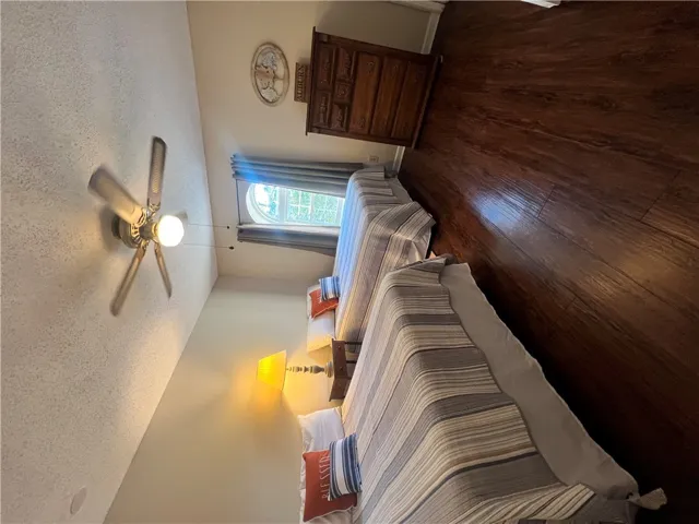 This cozy bedroom features durable wood flooring and abundant natural light through a distinctive window.