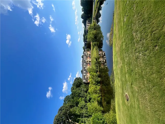 This scenic landscape captures buildings nestled beside a tranquil lake with lush greenery under a clear blue sky.
