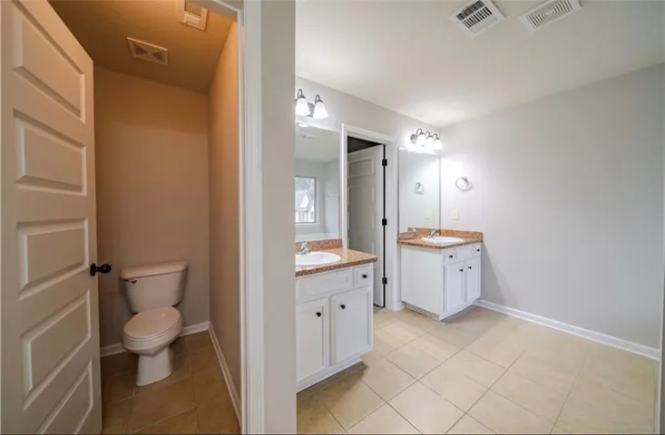 This spacious bathroom offers dual vanities and a private water closet.
