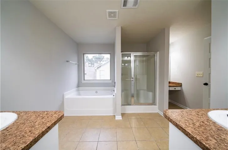 This primary bathroom features a shower, soaking tub, and tile flooring, offering a functional design.