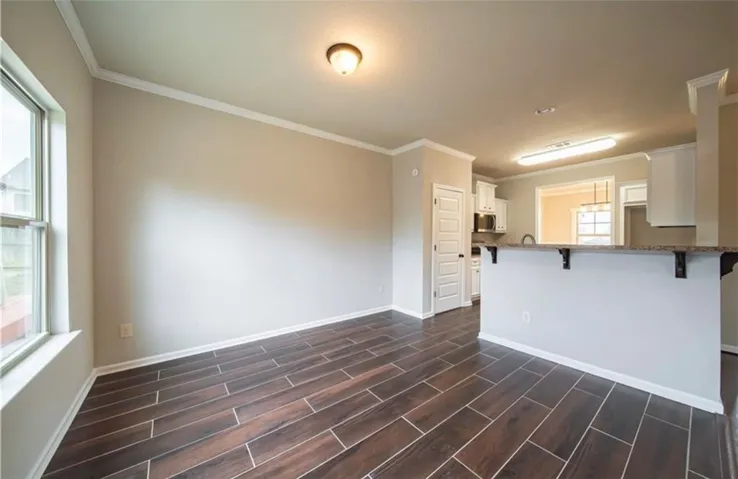 This inviting space features durable tile flooring, crown molding, and a kitchen with stainless steel appliances.