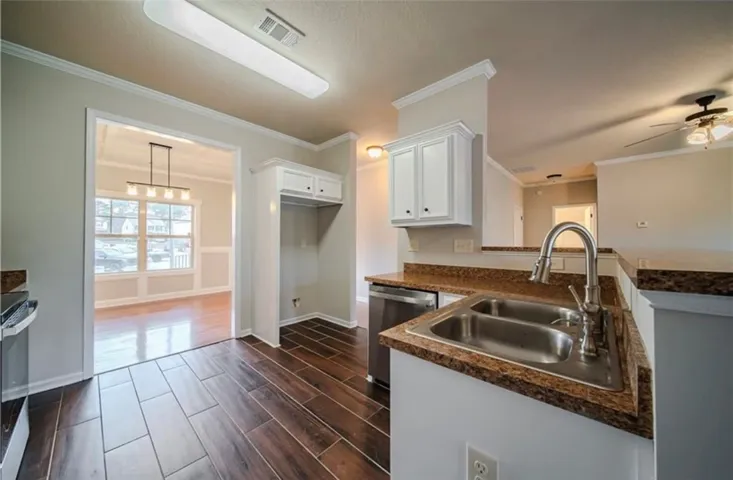 This kitchen features rich flooring and ample counter space, connecting to an adjacent room.