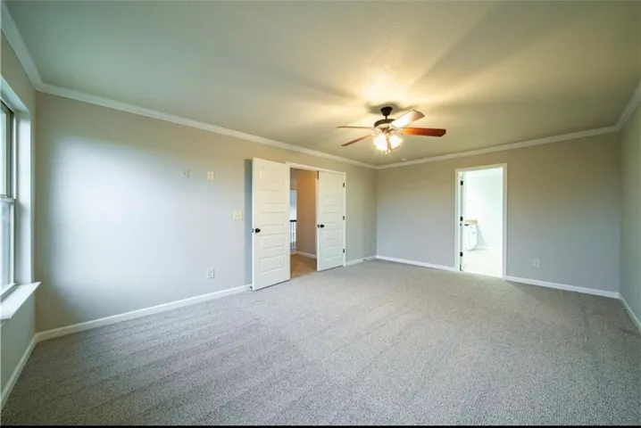 This spacious room features neutral tones and crown molding.