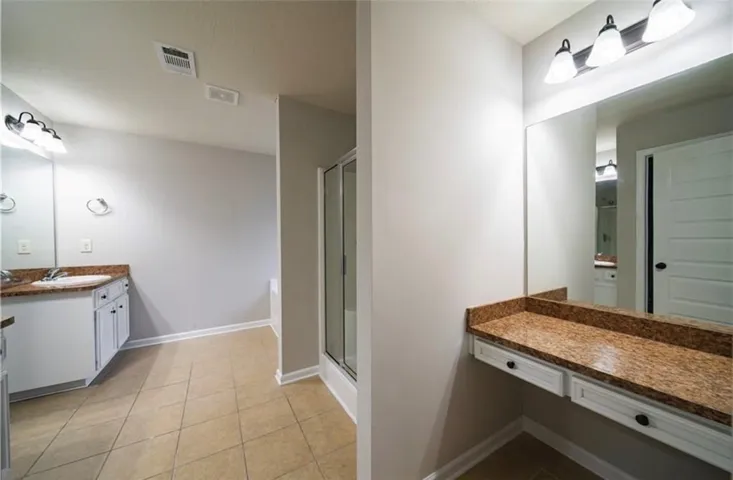 This spacious bathroom offers elegant granite counters and durable tile flooring.