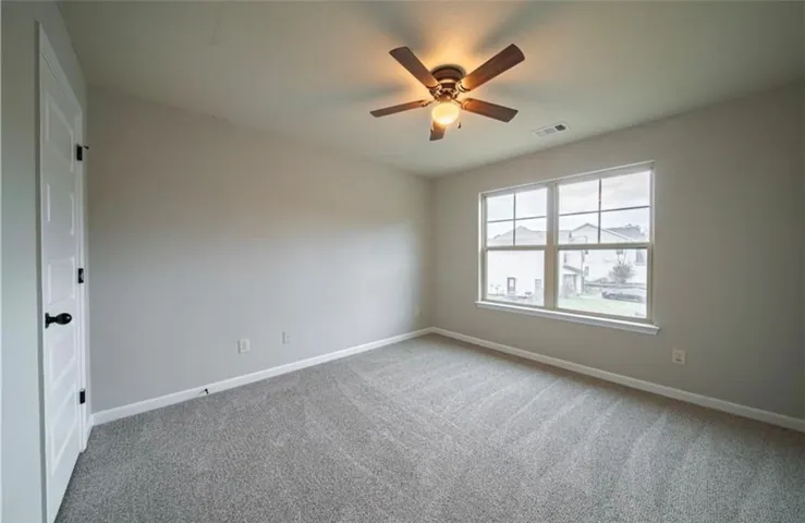 This spacious room features ample natural light and plush carpeting, ideal for comfortable living.
