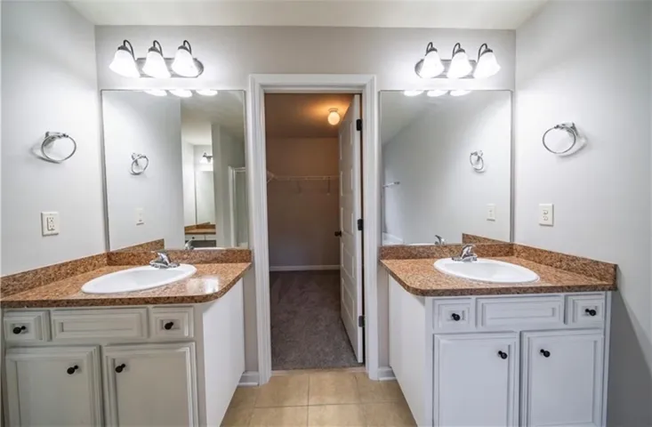 This bathroom features dual vanities, perfect for busy mornings, with a convenient walk-in closet beyond.