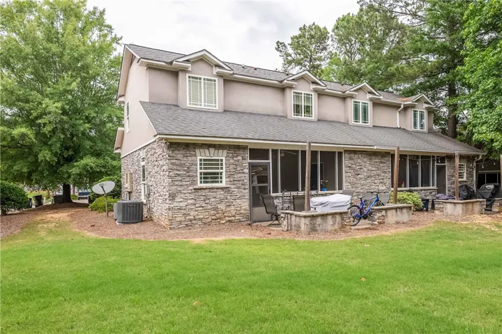 Stone veneer and dormer windows accent the rear of this multi-level home, featuring screened porches.