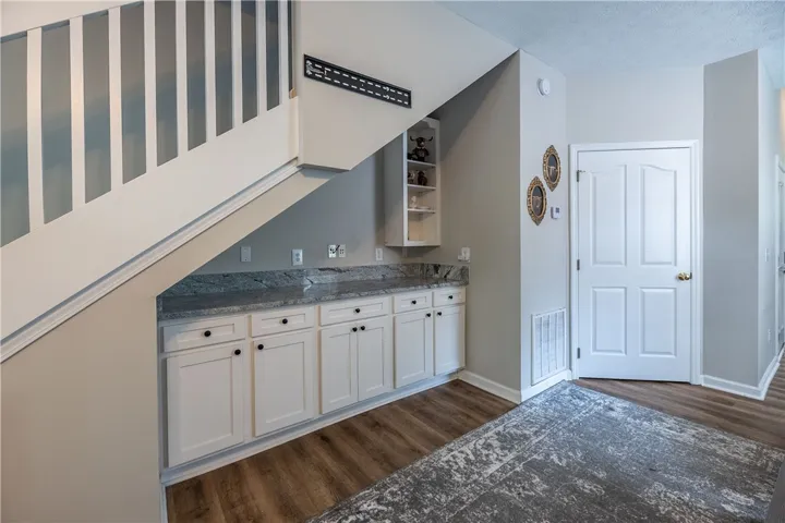 Functional cabinetry with granite counters provides clever storage beneath the staircase.