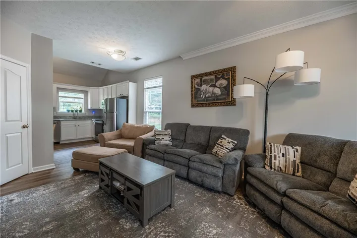 An open concept living area boasts elegant crown molding, connecting seamlessly to a well-appointed kitchen with modern amenities.