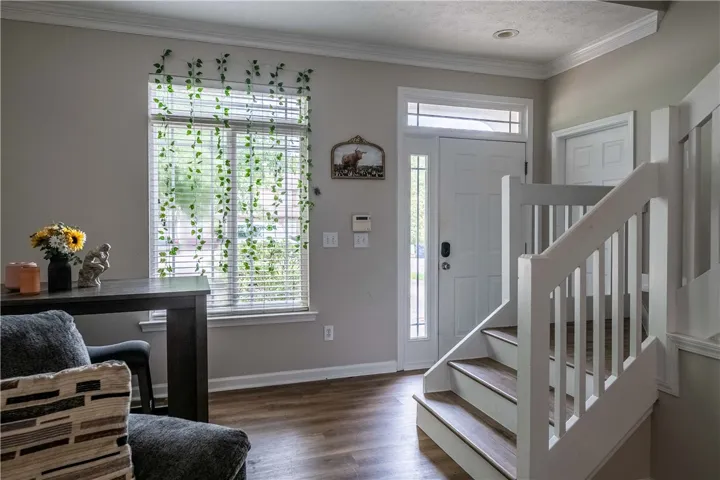 A welcoming entry area features rich wood flooring, a bright window, and an inviting staircase.