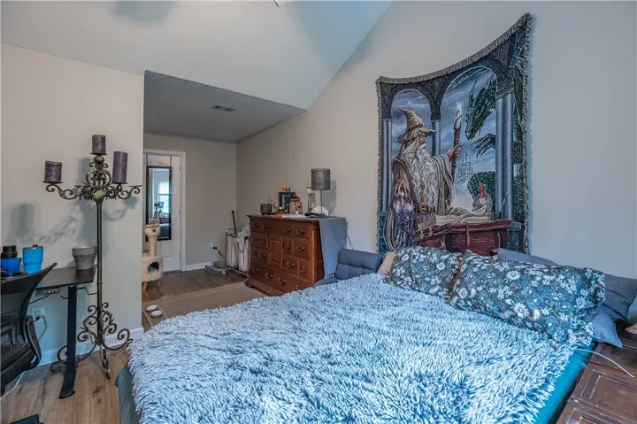 Slanted ceilings add character to this naturally illuminated bedroom with wood flooring.
